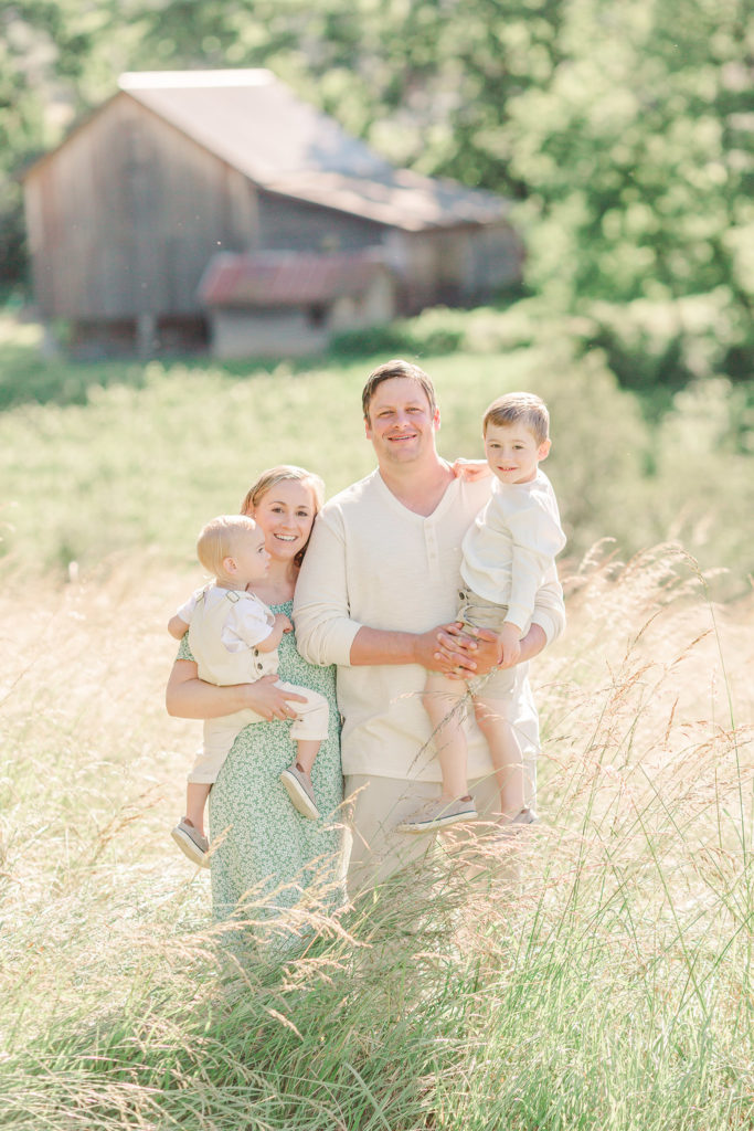 Family of four in a field wearing neutral cream colors and sage green