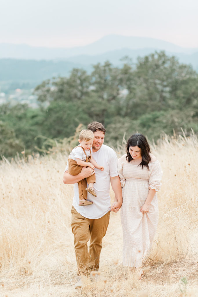 Family of three in a field wearing spring family photo outfits: neutral gingham family photos