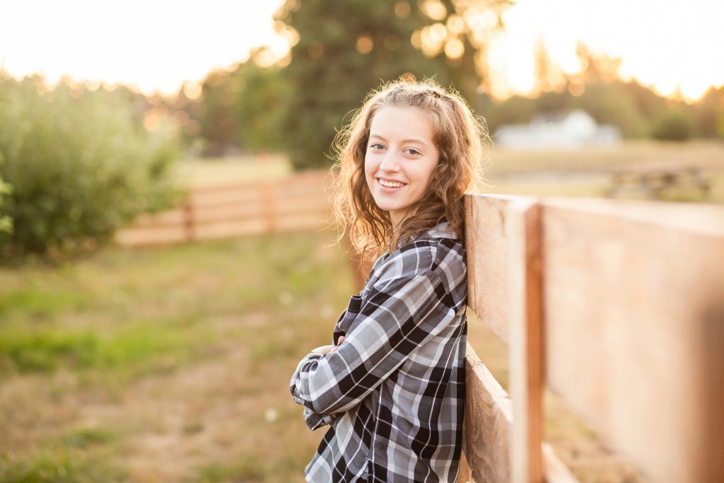 a girl stands next to a fence during her senior photo session