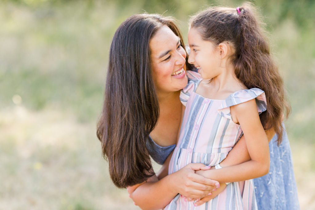 mom and daughter laugh together in a field near portland, oregon