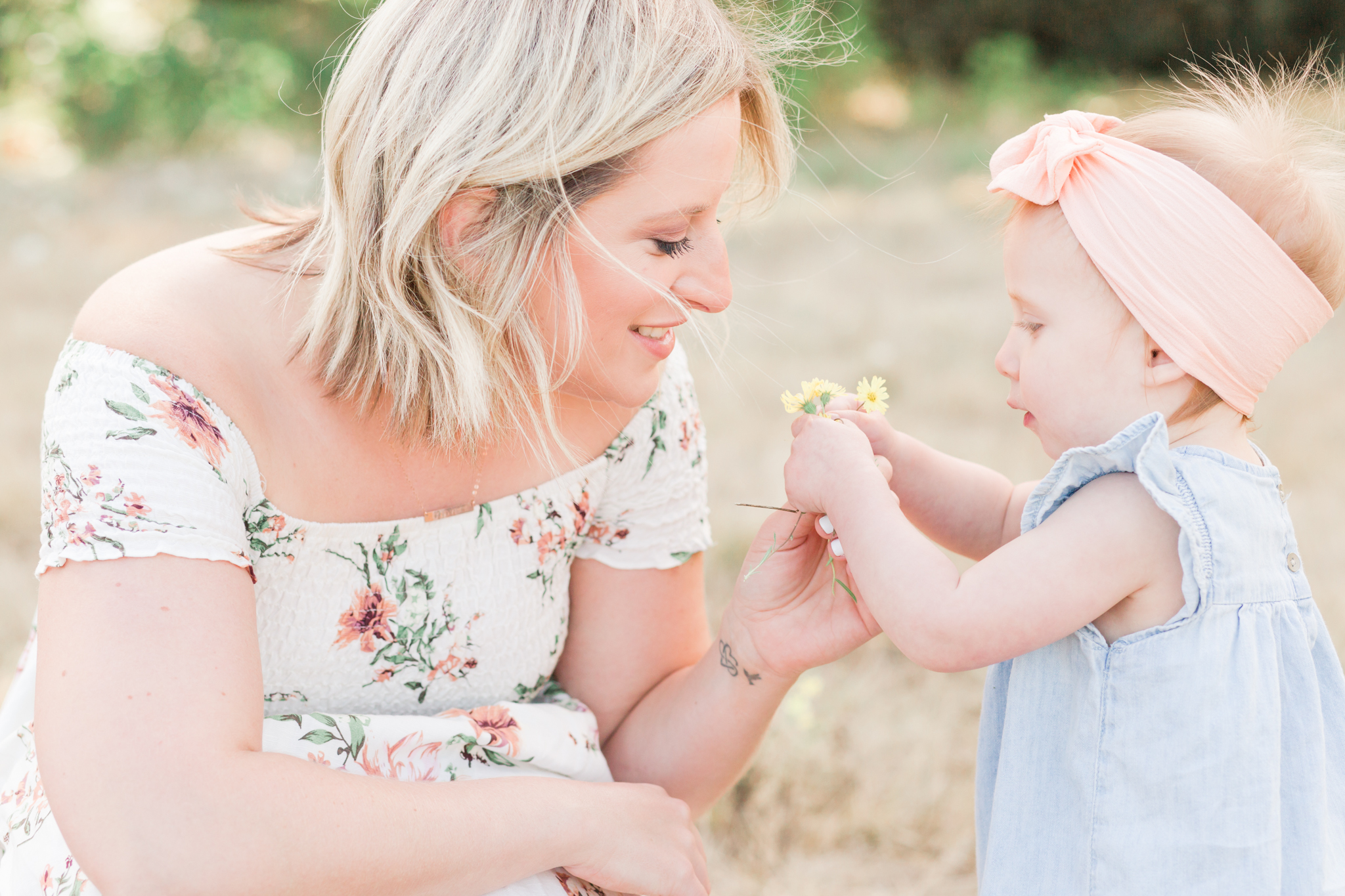 Mom and toddler daughter look at a flower