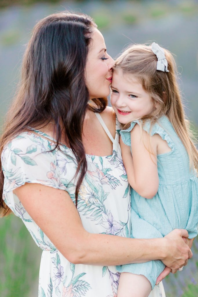 mom holding toddler daughter at their lavender field photoshoot