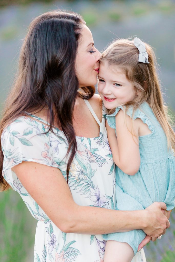mom holding toddler daughter at their lavender field photoshoot