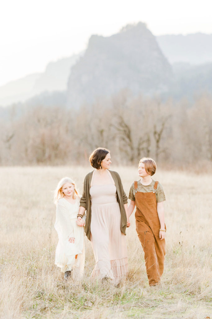 Family of 3 walking towards the camera with a mountain in the background, taken with a best lens for family portraits, the 135mm lens.