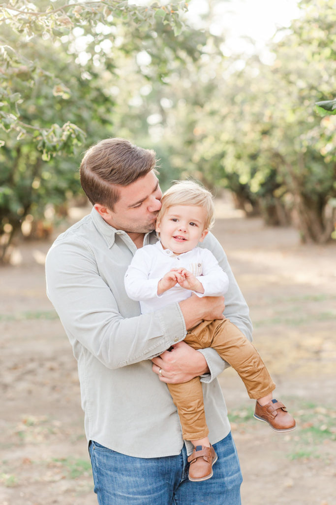 Dad holds son in hazelnut orchard
