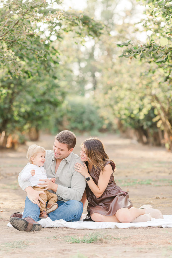 family of 3 sitting in hazelnut orchard by Portland portrait photographers Samantha Shannon