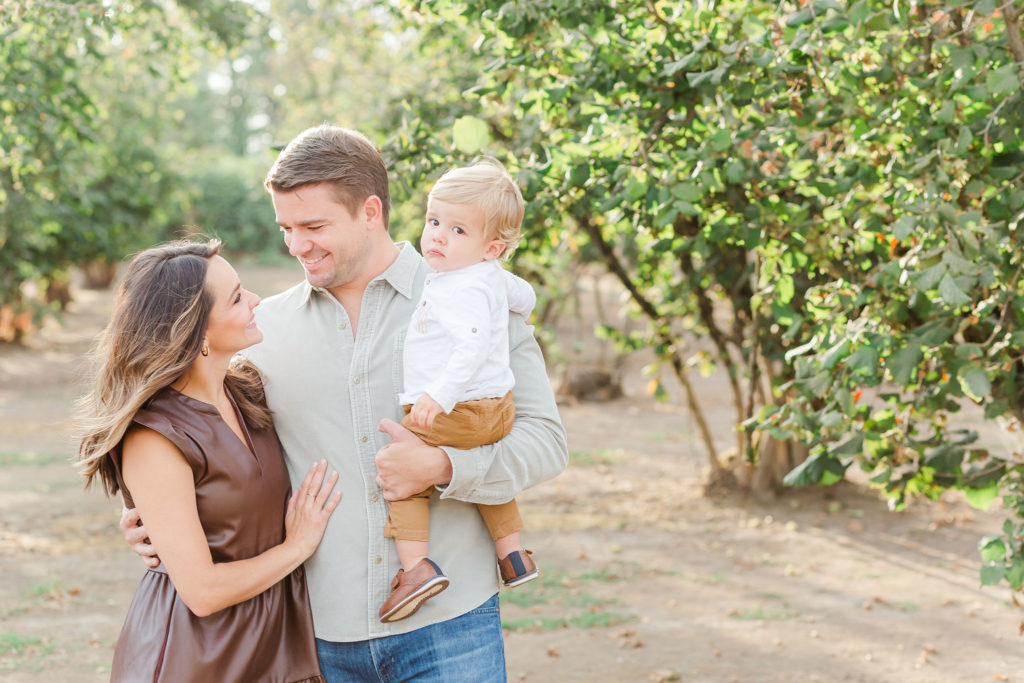 Mom, dad. and child stand in a hazelnut orchard for Portland family photos